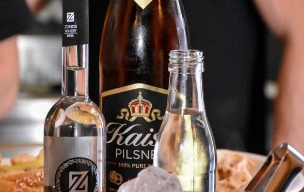 Μπουκάλι τσίπουρο, μπουκάλι μπύρας και παγοδοχείο σε τραπέζι του τσιπουράδικου Καϊξής στα Ιωάννινα
